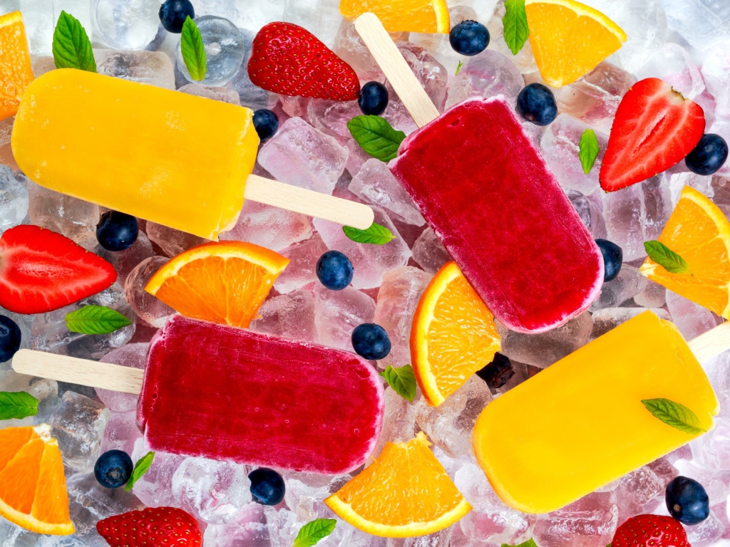 Разноцветное фруктовое мороженое с ягодами лежит на кусочках льда