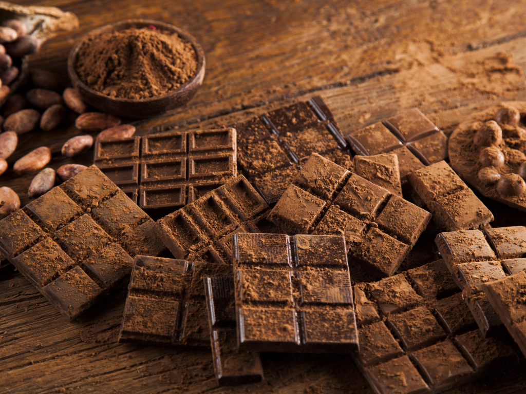 Плитки черного шоколада на столе с какао бобами