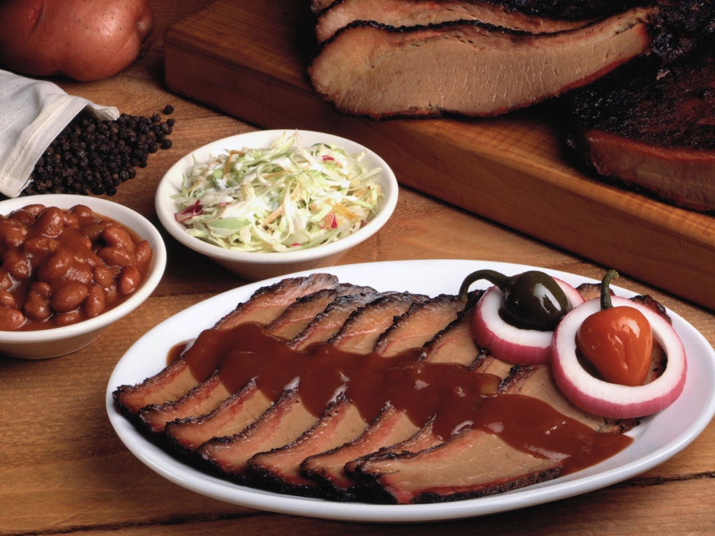 Аппетитные кусочки мяса барбекю на столе с овощами