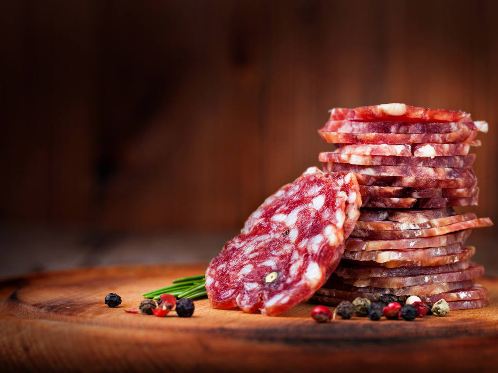 Нарезанная сухая колбаса на столе со специями