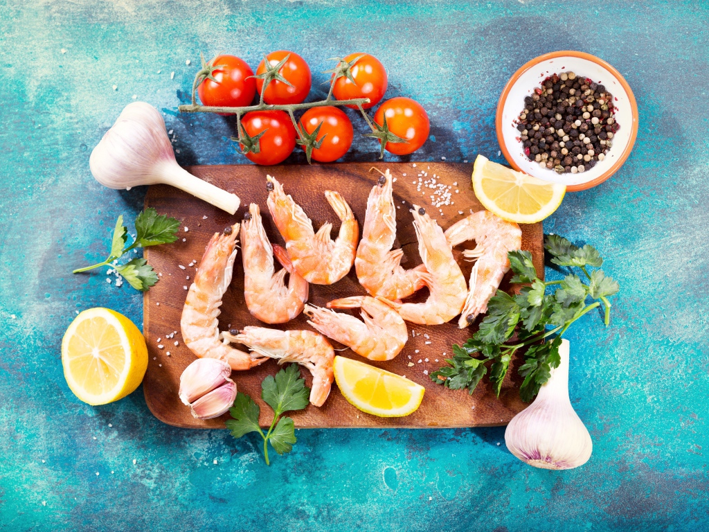 Креветки на разделочной доске с чесноком, лимоном и специями