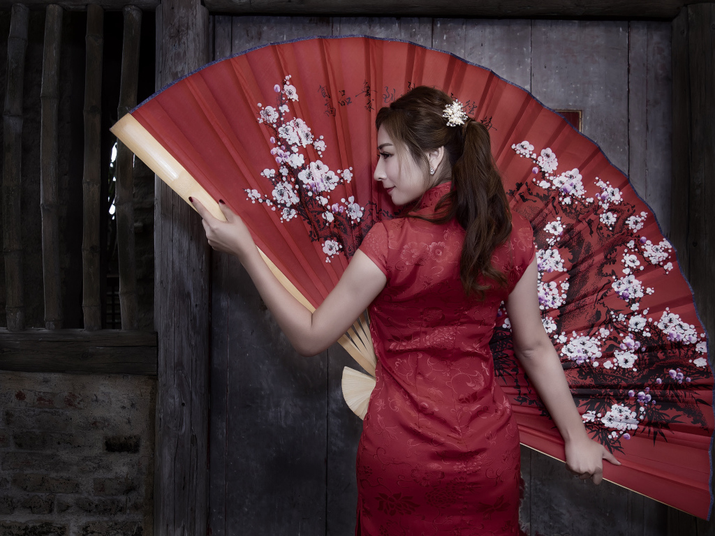 Красивая девушка азиатка в красном платье с большим веером