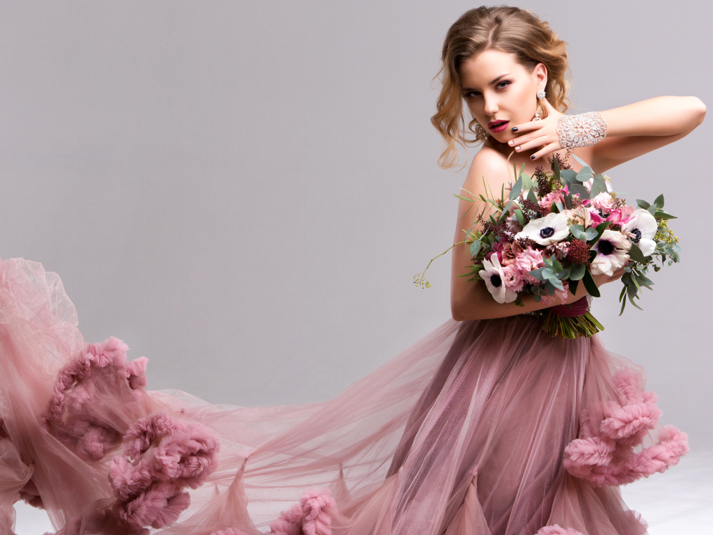 Эффектная девушка в красивом розовом платье с букетом цветов в руках