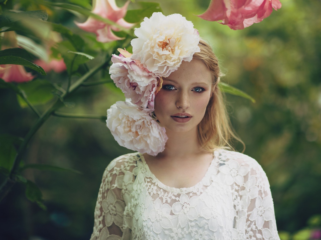 Красивая девушка в белом платье с большими пионами в волосах 