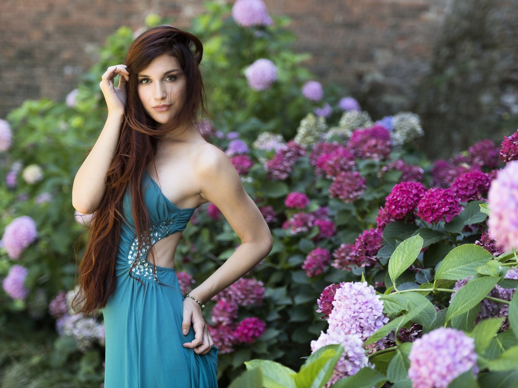 Красивая девушка модель в зеленом платье рядом с цветами гортензии
