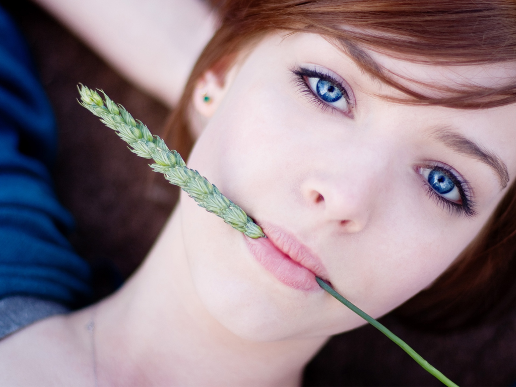 Красивая девушка с голубыми глазами с колоском во рту 