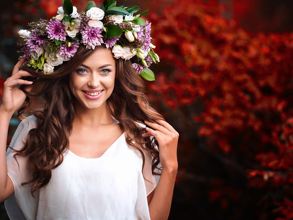 Красивая улыбающаяся девушка с венком из живых цветов на голове 