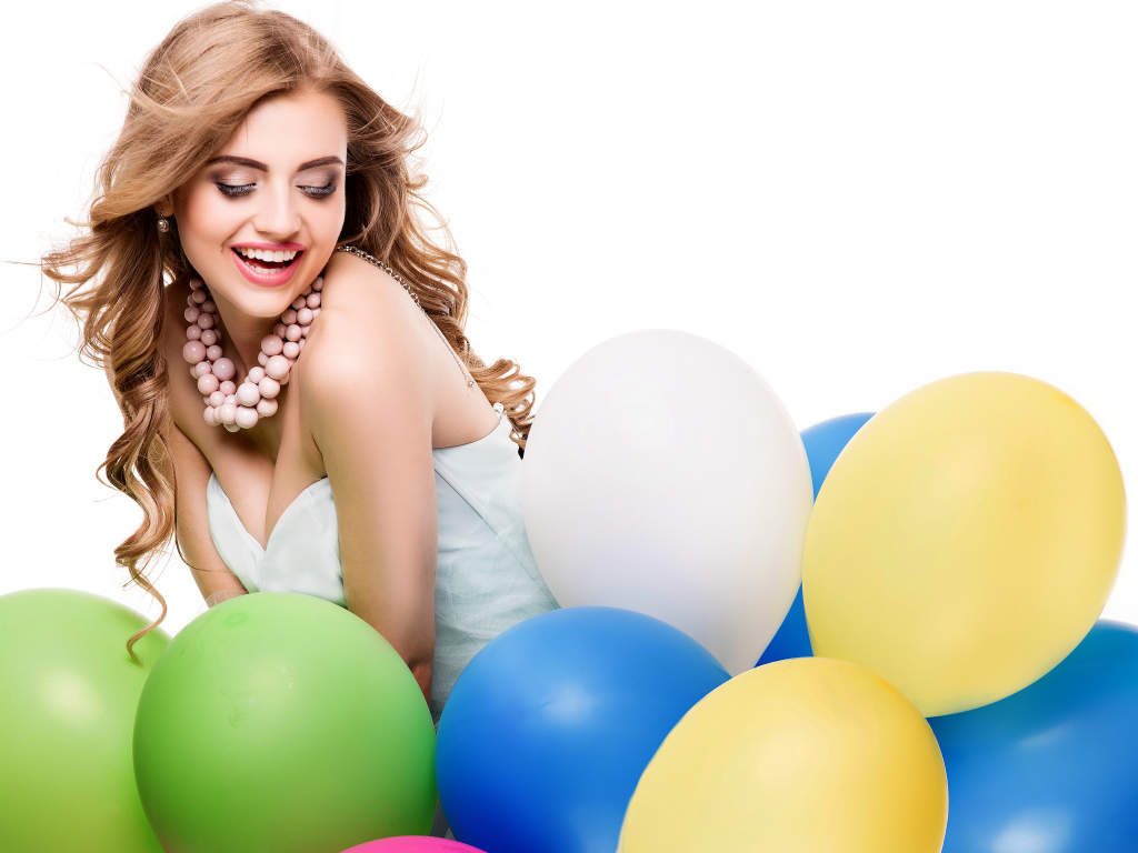 Красивая улыбающаяся девушка с разноцветными шариками на белом фоне