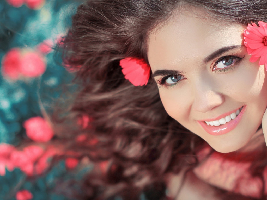 Красивая улыбающаяся девушка с розовыми цветами в волосах 