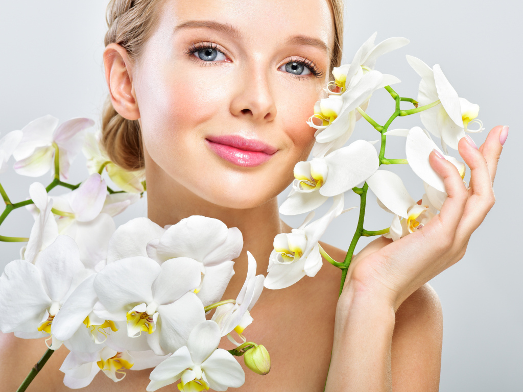 Нежная голубоглазая девушка с цветами орхидеи в руках