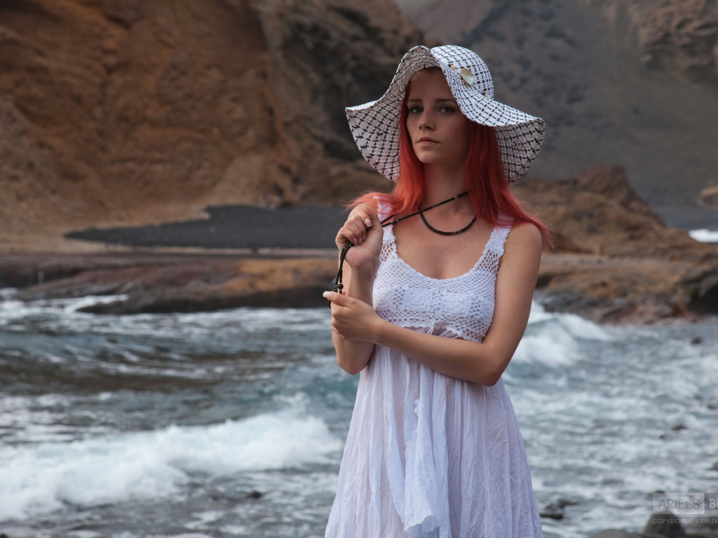 Рыжеволосая девушка в шляпе и белом платье у реки