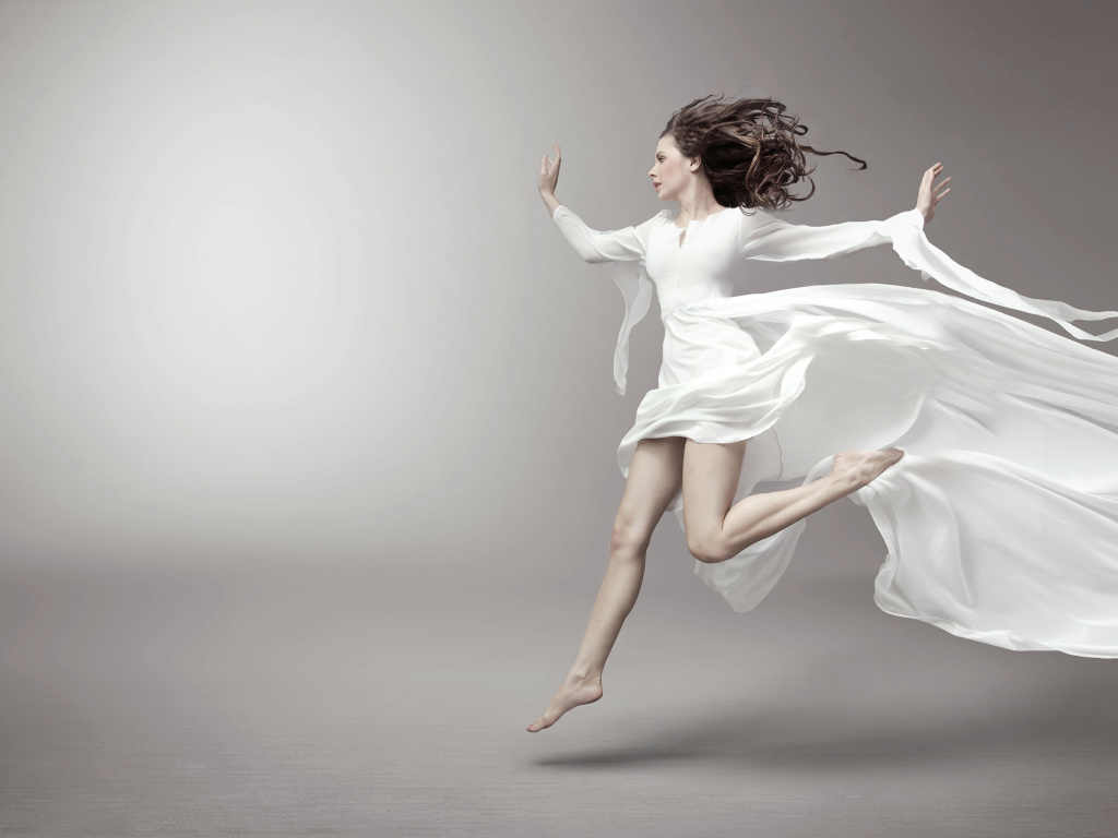 Бегущая красивая девушка в белом платье на сером фоне