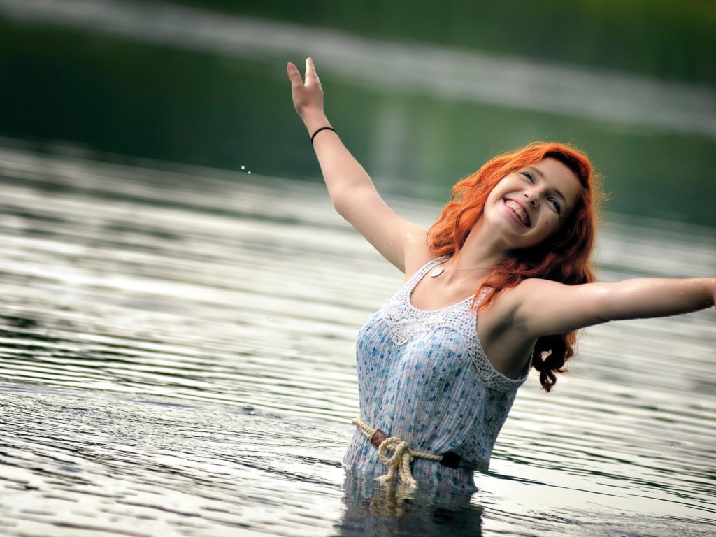 Улыбающаяся рыжеволосая девушка в воде 