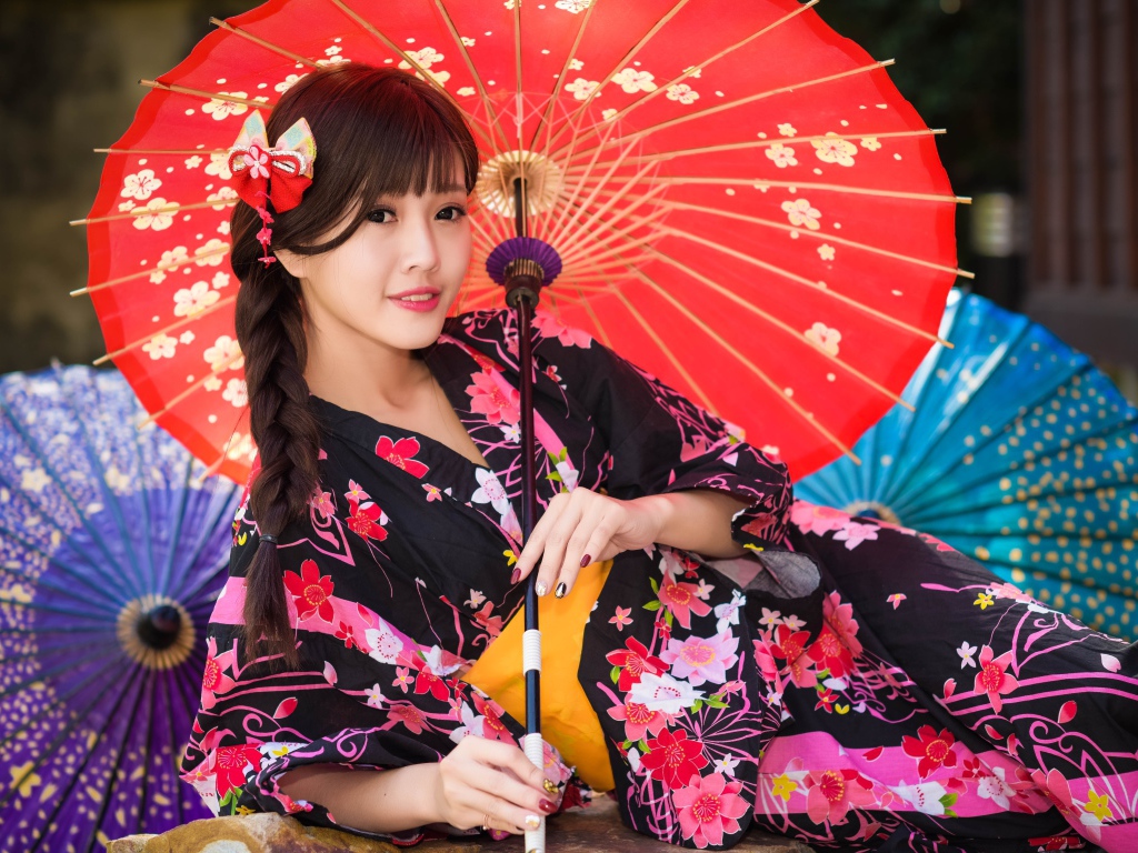 Молодая азиатка в кимоно с разноцветными зонтиками