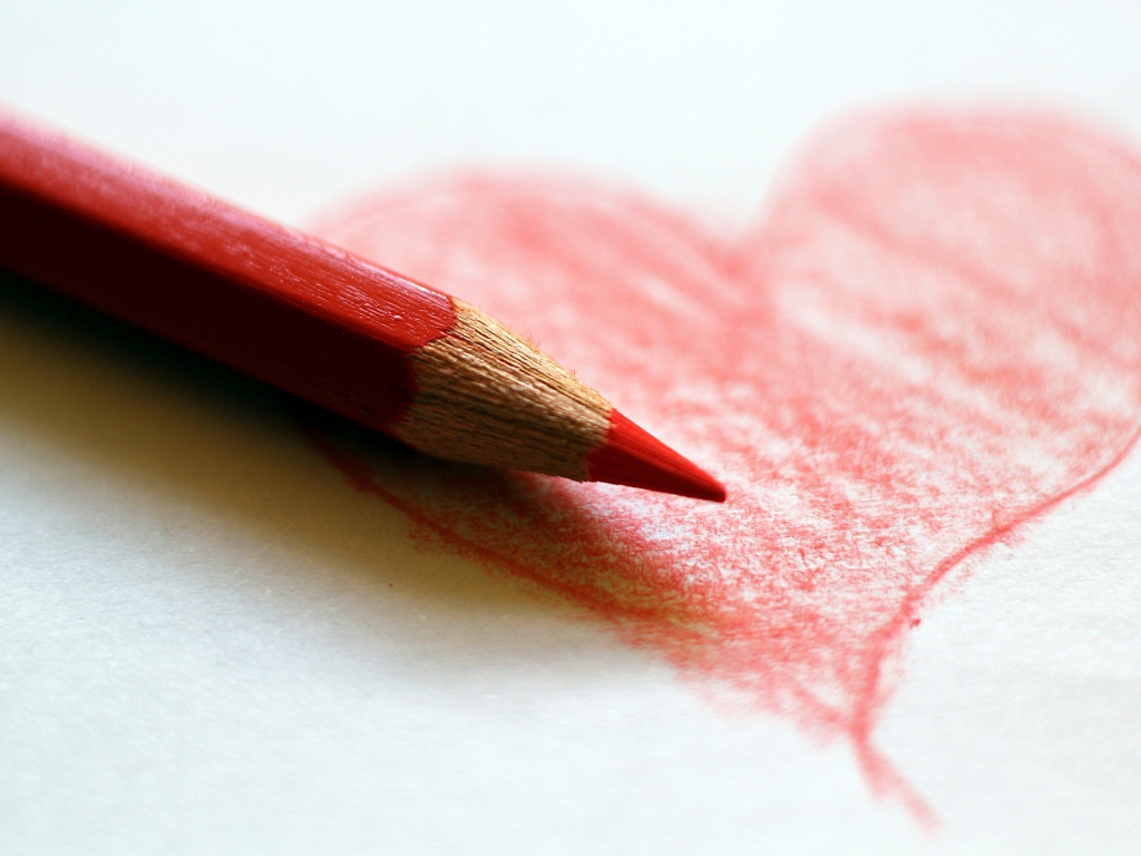 Нарисованное карандашом красное сердце на бумаге