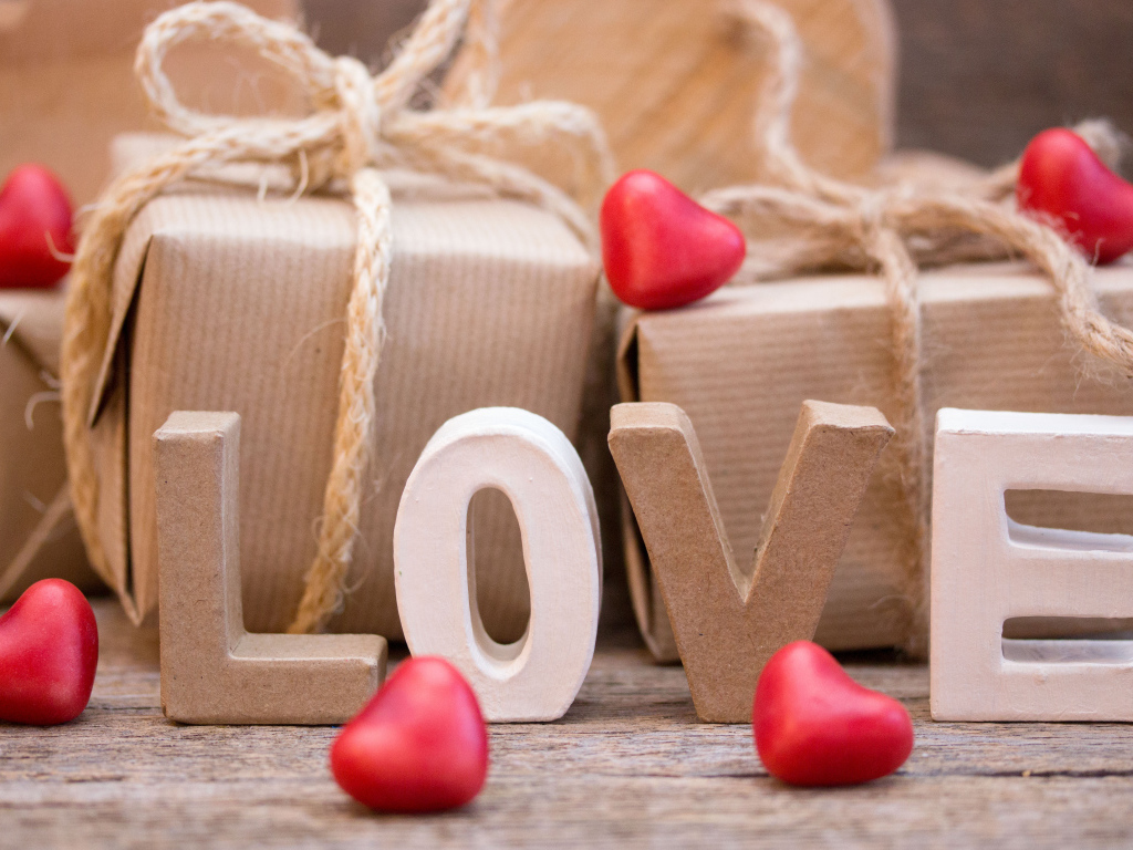 Романтические подарки и надпись Love с красными сердечками