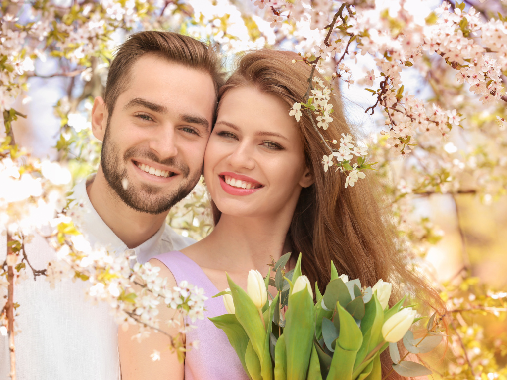 Улыбающаяся влюбленная пара у цветущего дерева