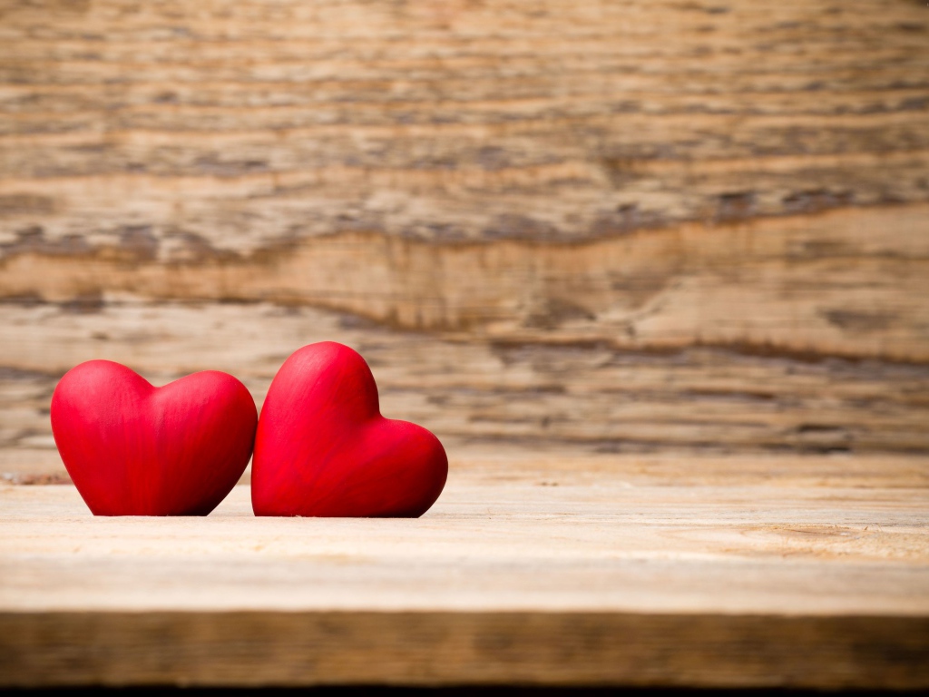 Два красных сердца лежат на деревянной лавке