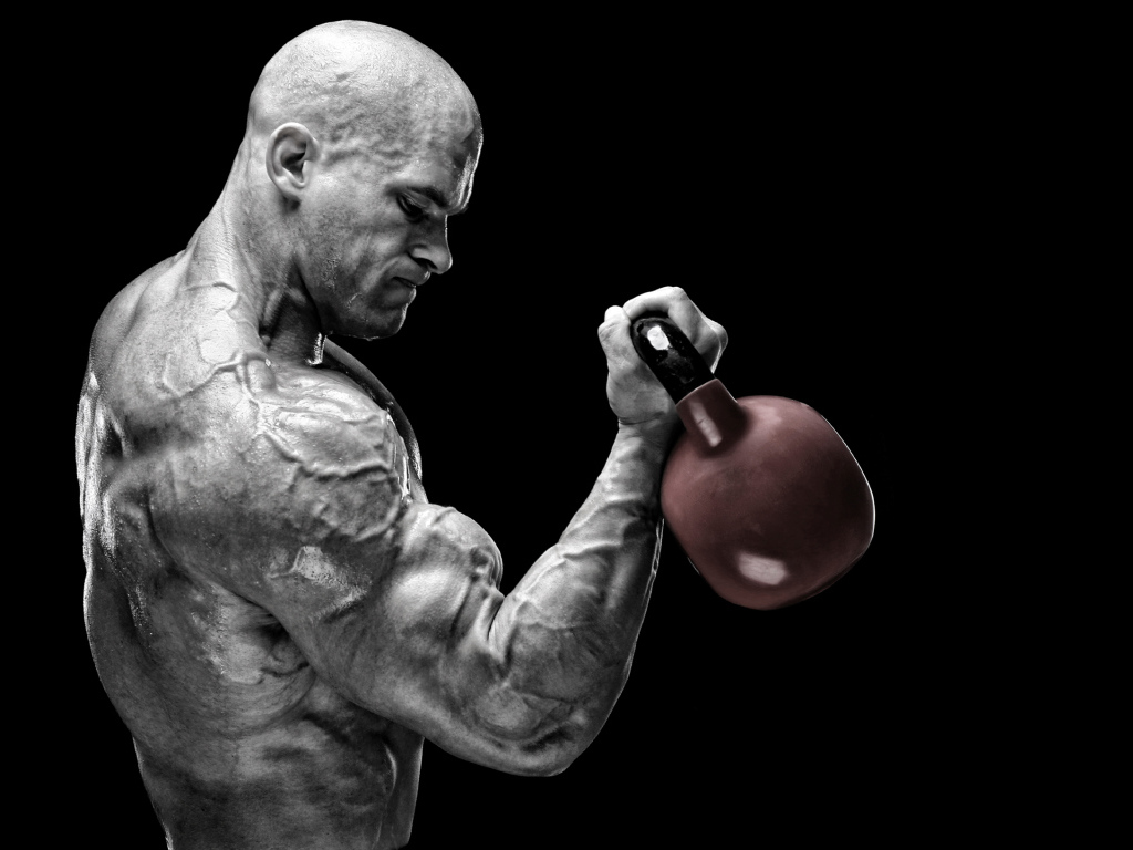 Сильный накаченный мужчина бодибилдер с гантелей в руках