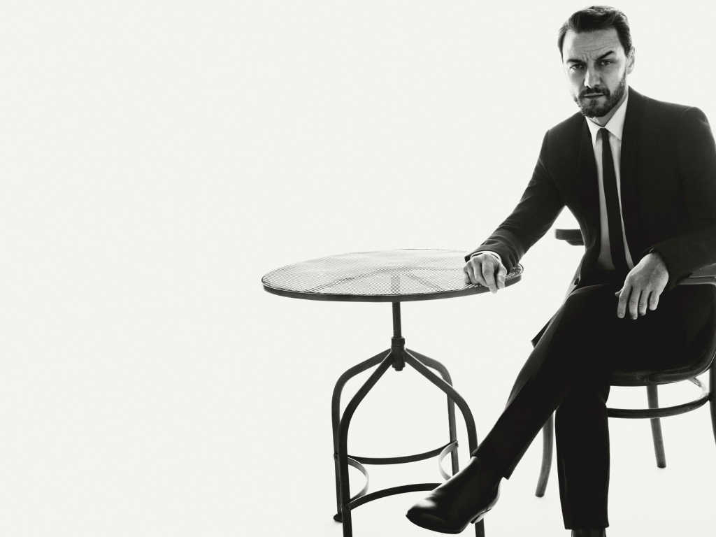 Актер Джеймс Макэвой сидит на стуле за столом черно-белое фото