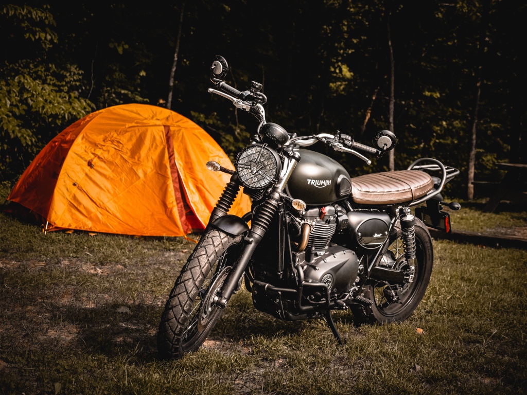 Черный мотоцикл Triumph на фоне оранжевой палатки