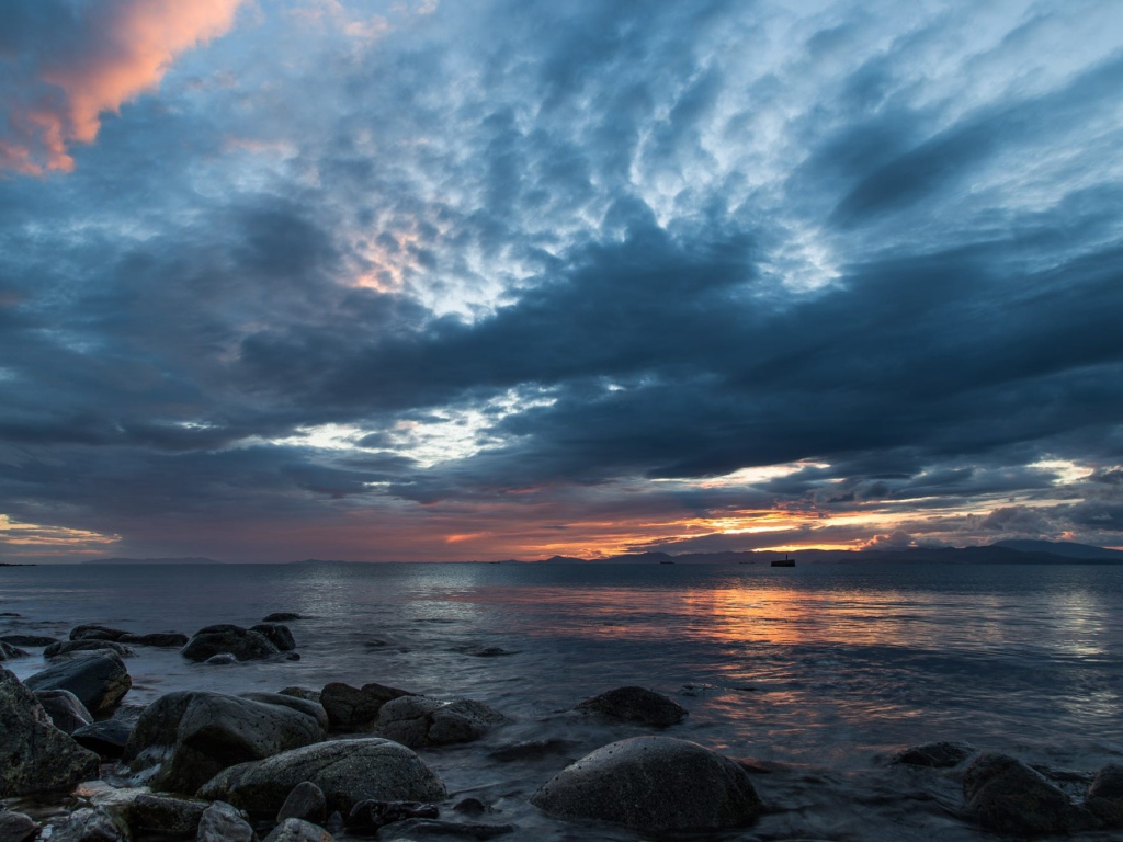 Валуны в воде на берегу на фоне пасмурного неба 