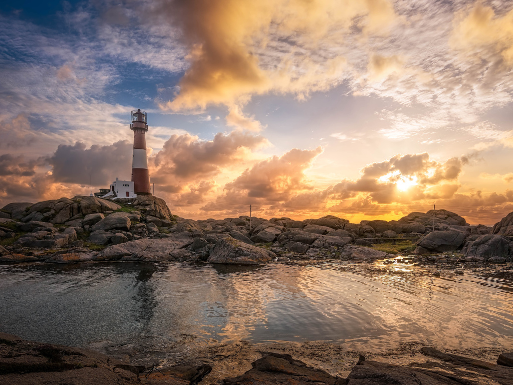 Маяк на каменном побережье на фоне красивого неба