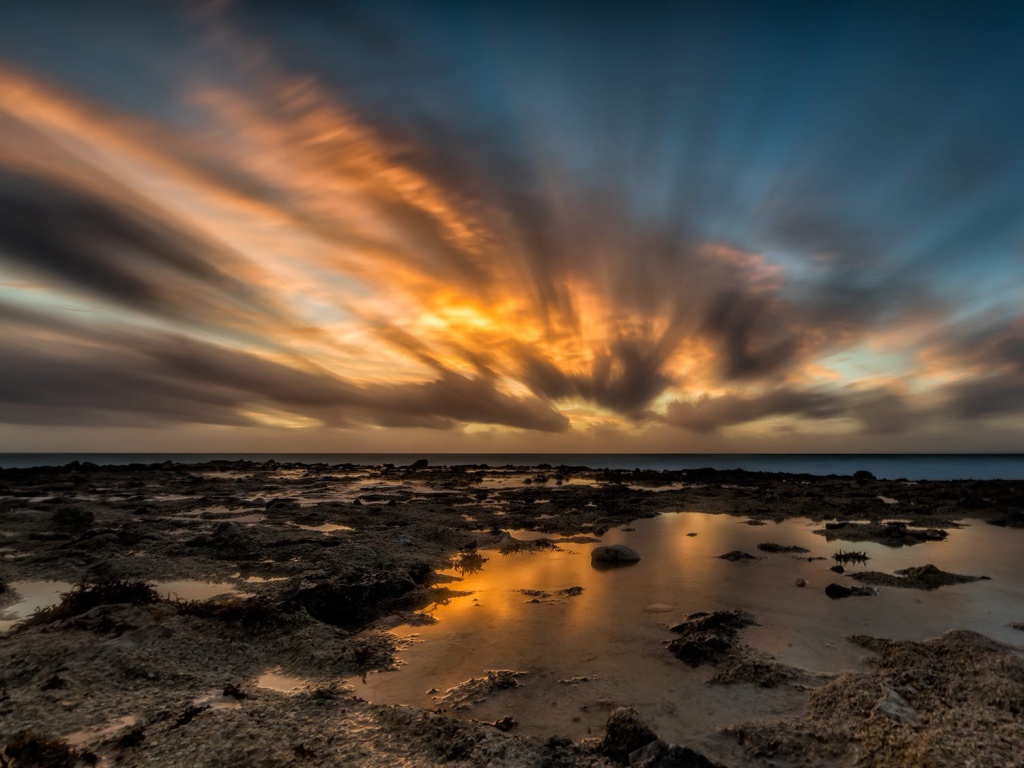 Закат солнца в облаках над водой 