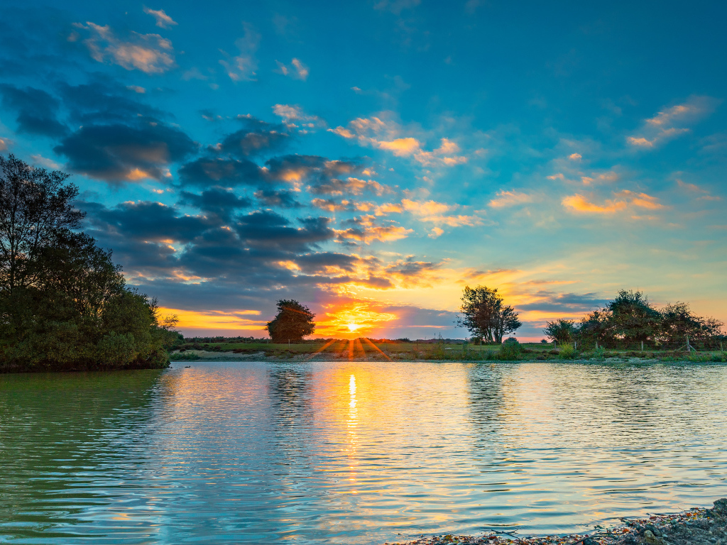 Закат солнца в небе отражается в воде озера 