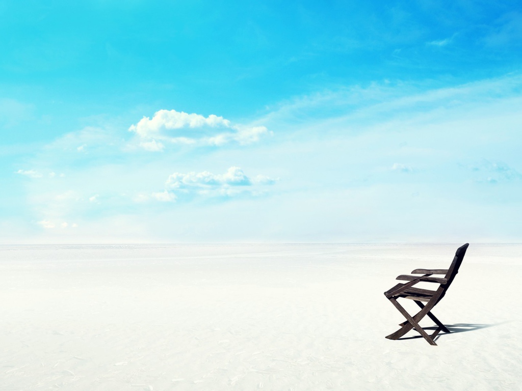 Шезлонг на белом песке на фоне голубого неба