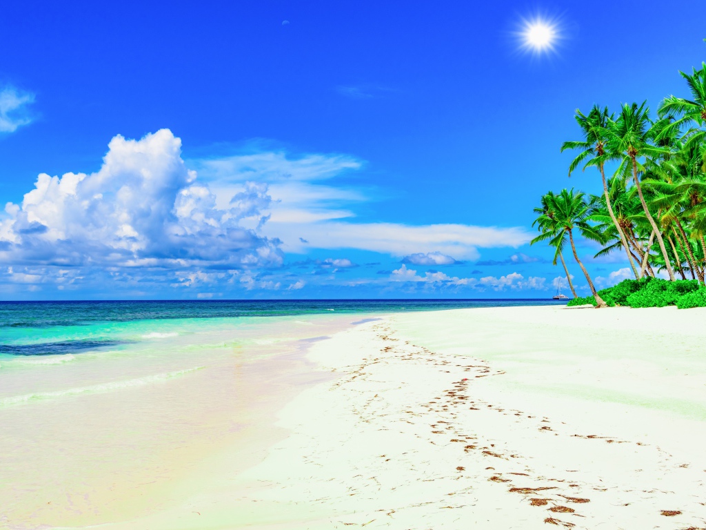 Следы на белом песке на тропическом пляже под красивым голубым небом