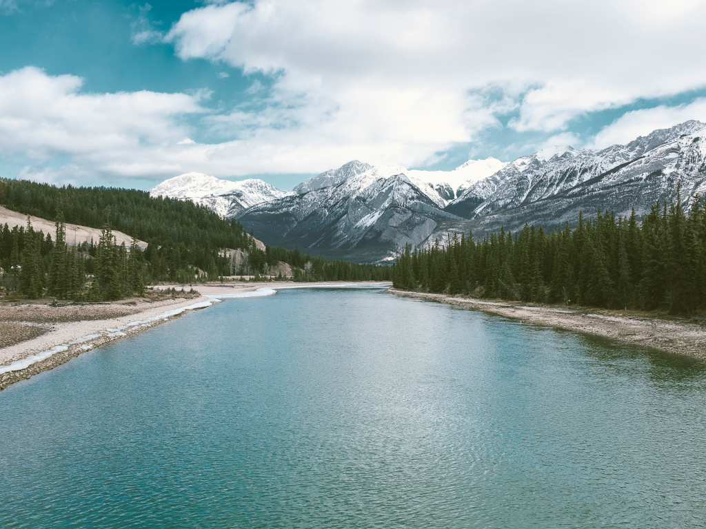 Чистая голубая вода в реке на фоне заснеженных гор 