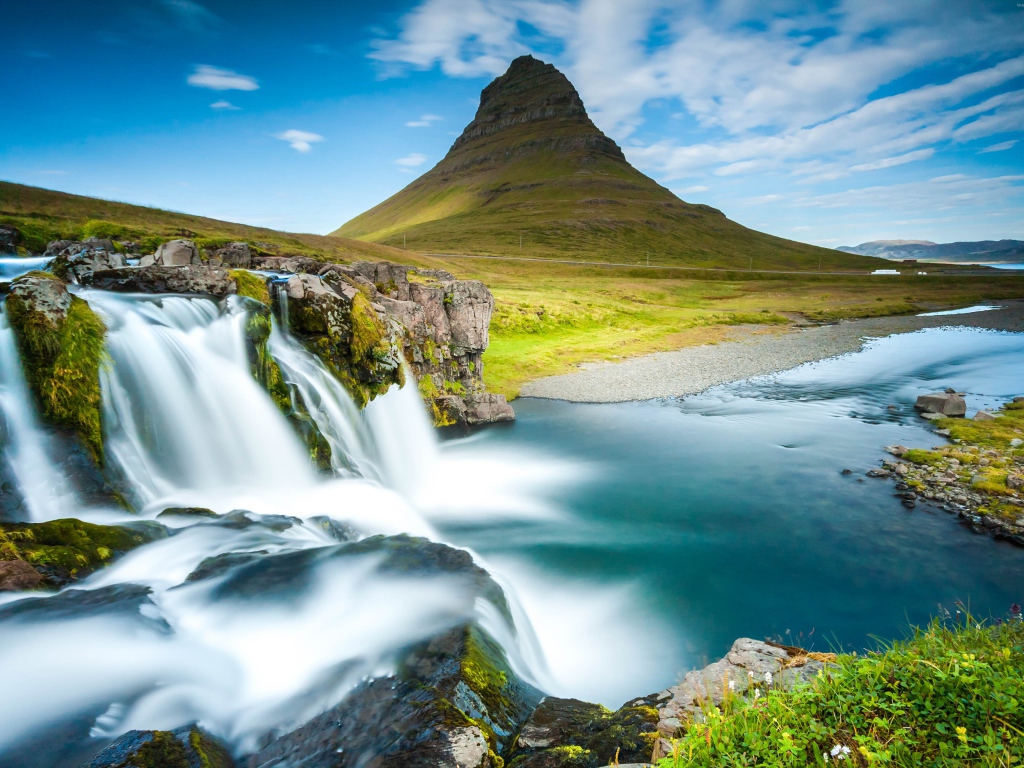 Водопад стекает в реку на фоне горы под красивым небом