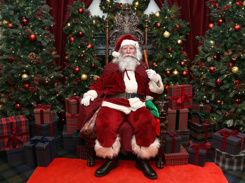 Санта Клаус курит трубку сидя в кресле
