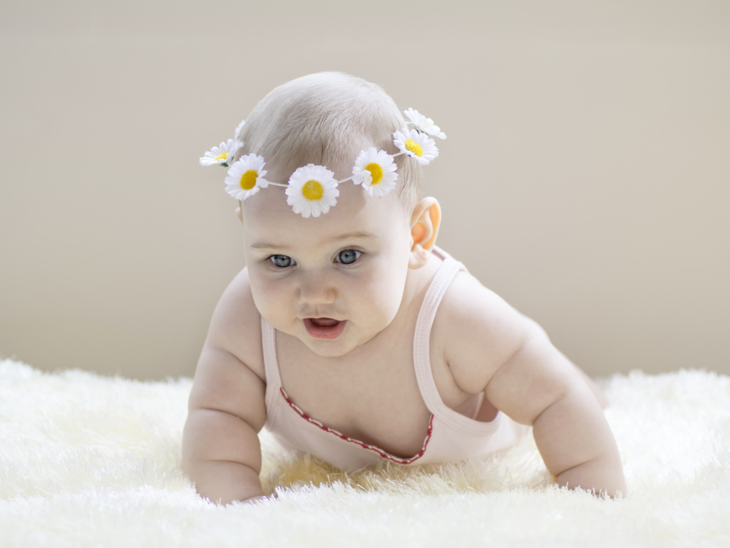 Грудной ребенок с венком из белых ромашек на голове