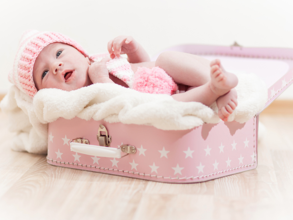 Милый младенец лежит в розовом чемодане