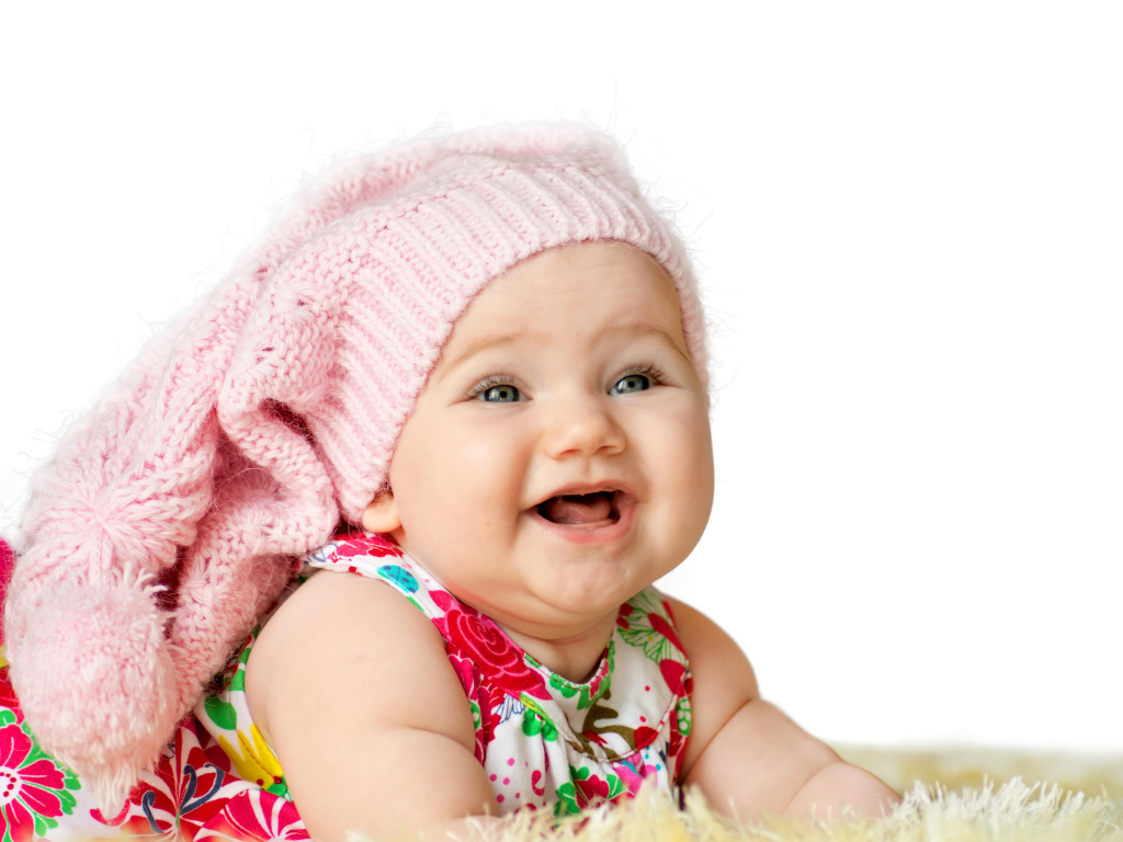 Милая маленькая улыбающаяся девочка в большой розовой шапке