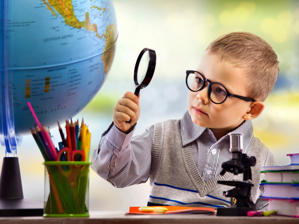 Маленький мальчик в очках исследует глобус