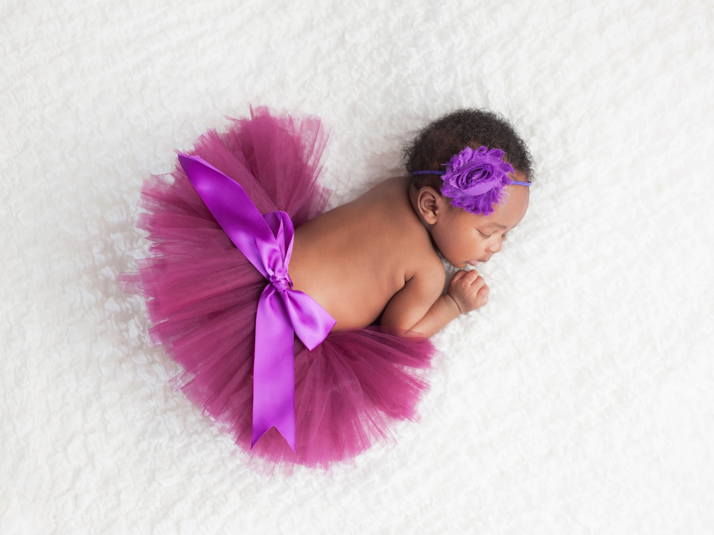 Маленькая девочка в красивой пышной юбке спит на белом покрывале