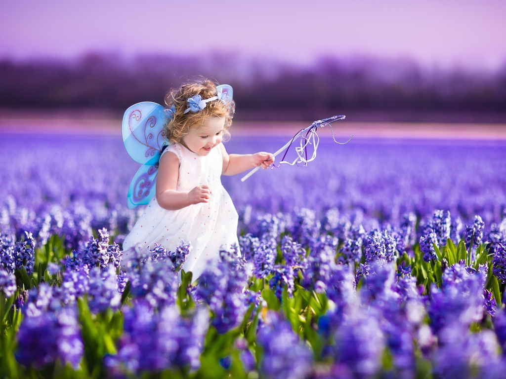 Маленькая девочка в костюме феи гуляет по полю гиацинтов