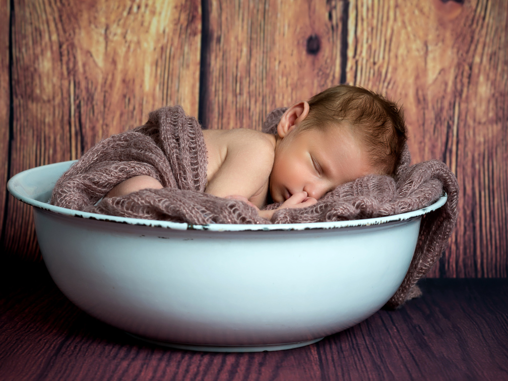 Новорожденный ребенок спит в белой миске