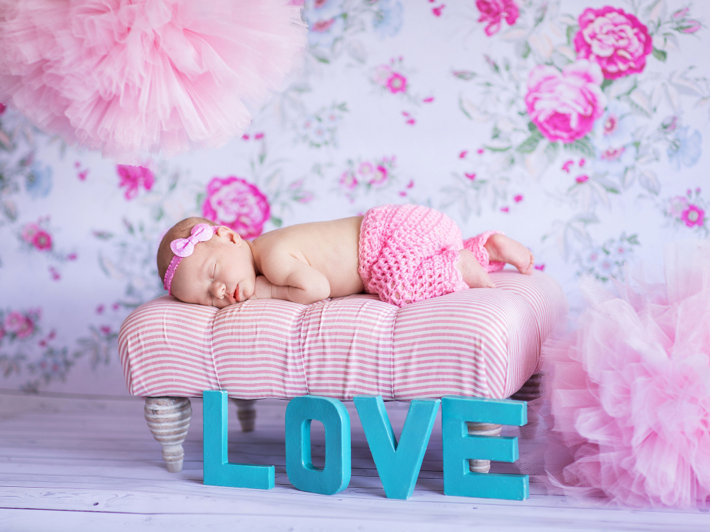 Спящий грудной ребенок в розовом костюме и надписью love