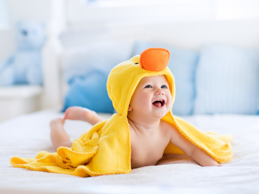 Маленький улыбающийся грудной ребенок в костюме утенка