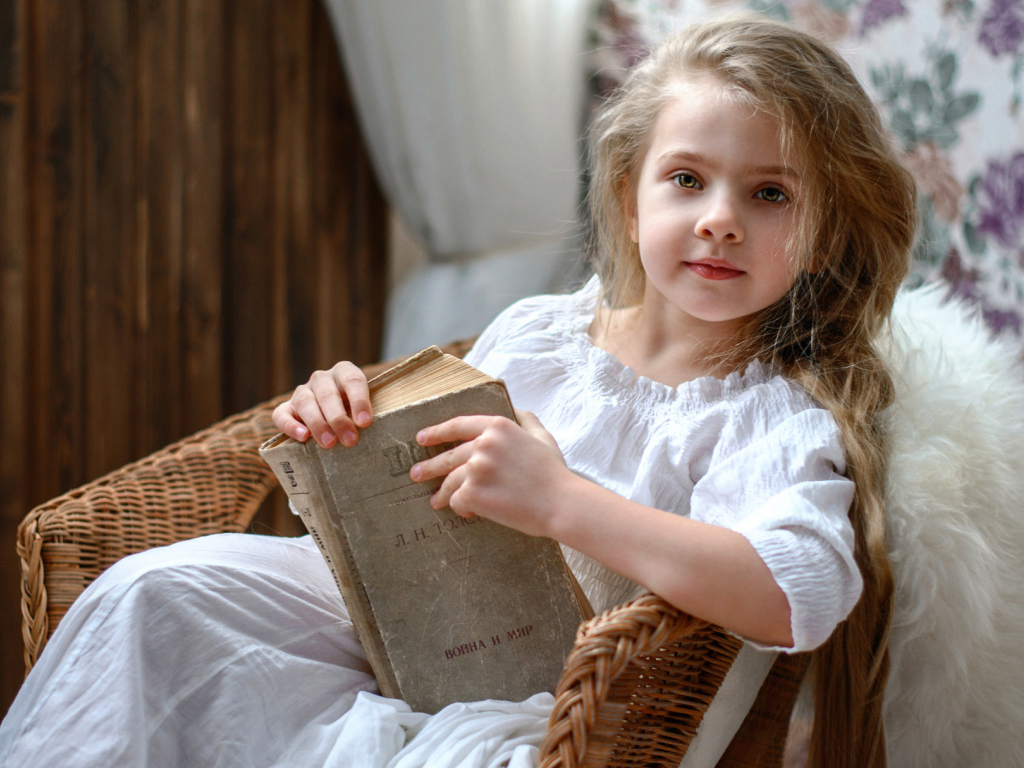 Красивая маленькая девочка в белом платье с книгой 