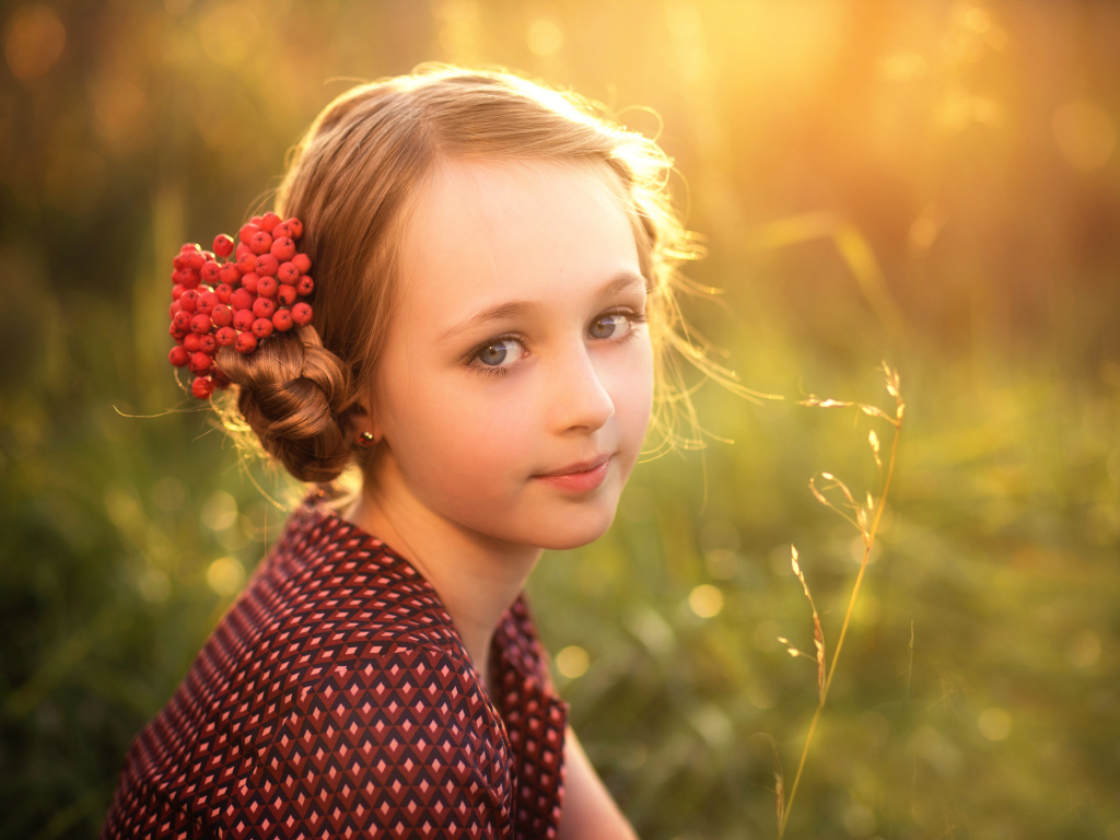 Красивая маленькая девочка с ягодами калины в волосах