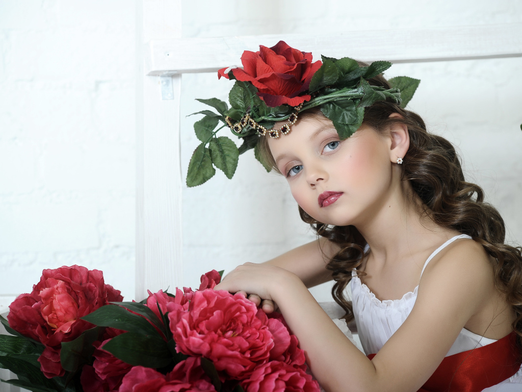 Красивая маленькая девочка с венком из роз на голове