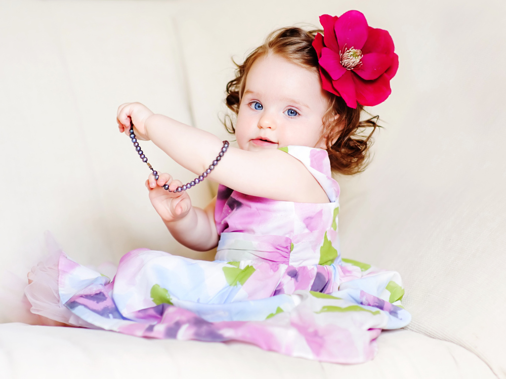 Маленькая голубоглазая девочка с красным цветком в волосах