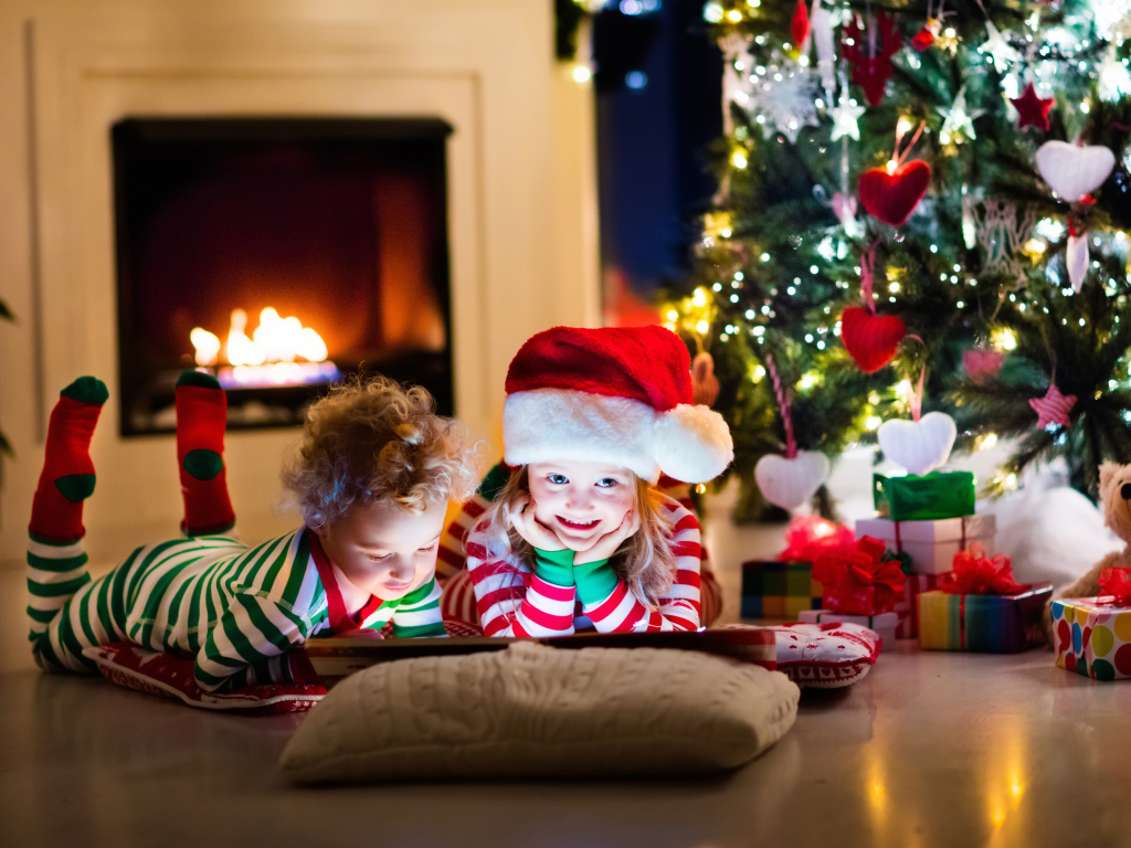 Маленькие дети в новогодних костюмах под елкой