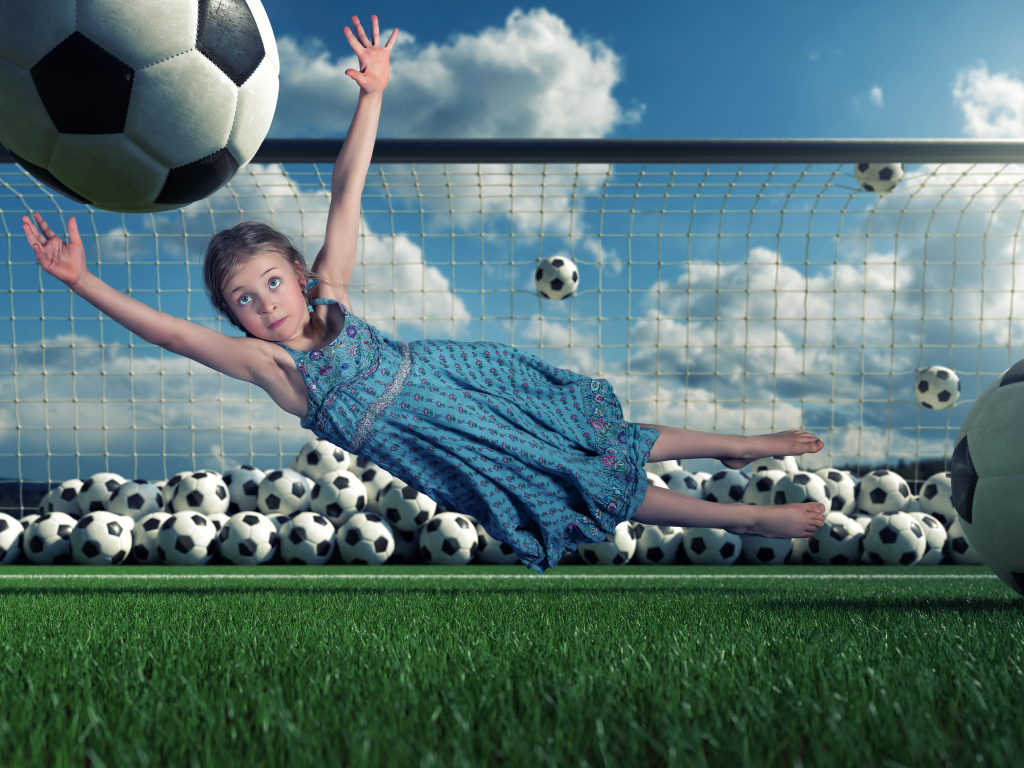 Маленькая девочка вратарь ловит мяч в воротах