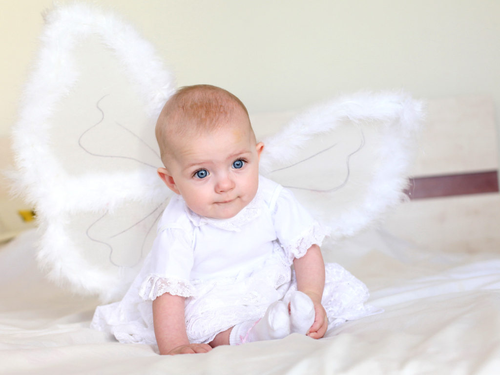 Маленькая девочка в красивом белом платье с крыльями